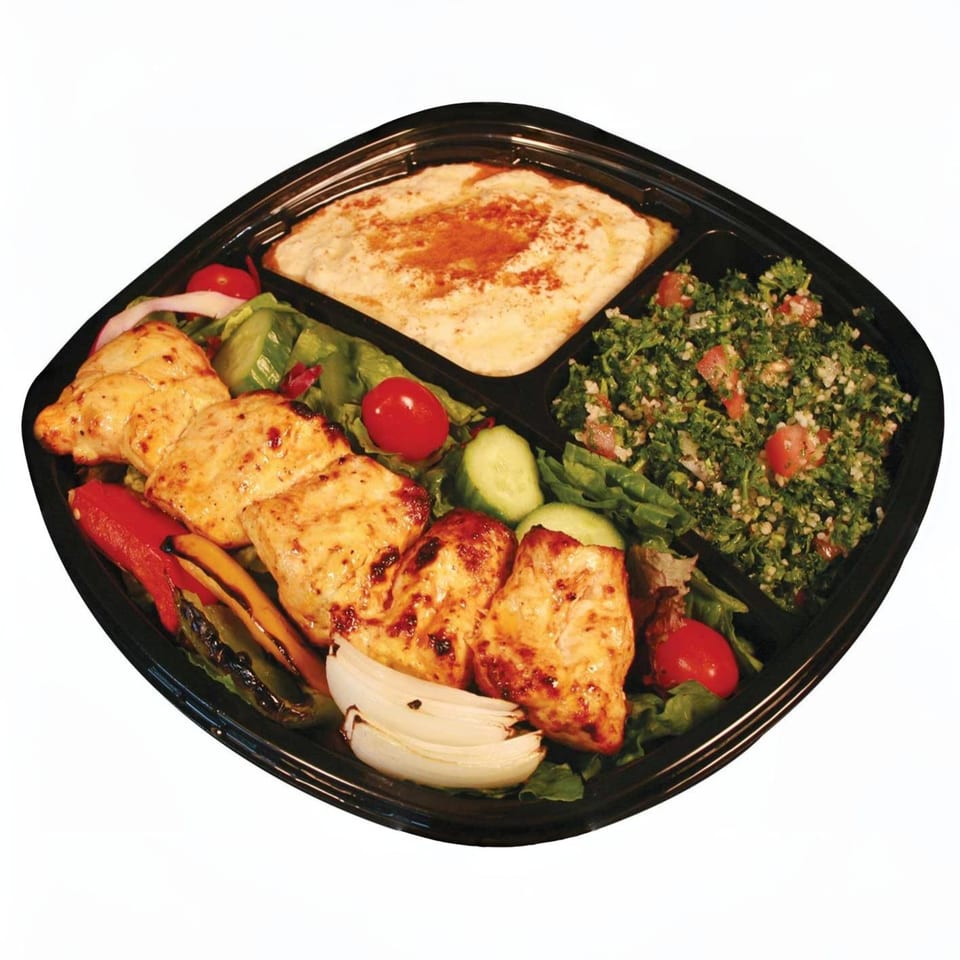 Mediterranean chicken plate with hummus, tabbouleh, grilled vegetables, and salad in a black tray.