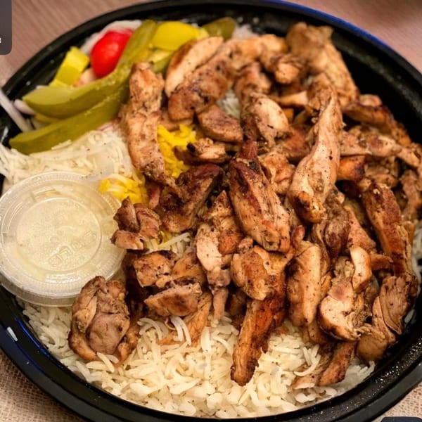 Caspian Mediterranean Grill's chicken shawarma plate with rice, pickles, and a side of sauce.
